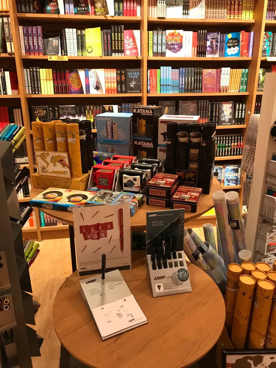 Bookstore display with colorful novels, stationery, maps, pens, and quirky office gifts.